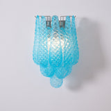 The blue sconce lit, light passing through the patterned glass