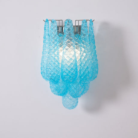 The blue sconce lit, light passing through the patterned glass