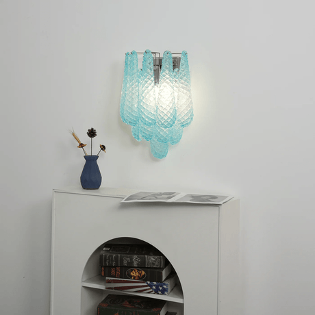 The blue sconce above a white cabinet with an arched niche and books