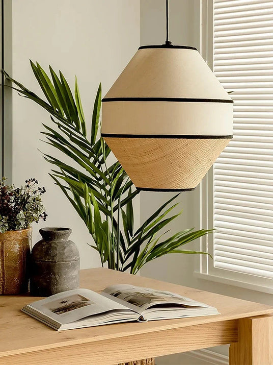 Woven willow shade lit above a table with a plant