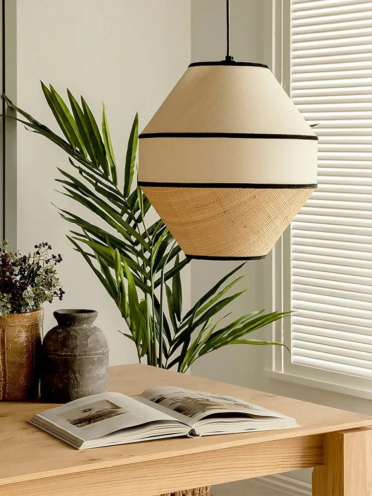Woven willow shade lit above a table with a plant