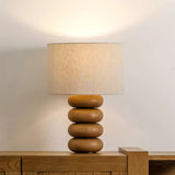 Stacked sphere table lamp unlit on a wood sideboard in a bright hallway