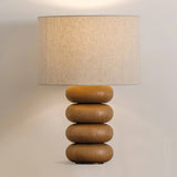 Close view of the lit linen drum above three flattened wood spheres