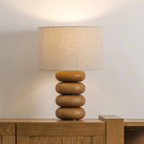 Stacked sphere table lamp lit on a wood sideboard against a pale wall