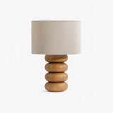 Stacked wood sphere lamp seen from an angle with an off white drum shade