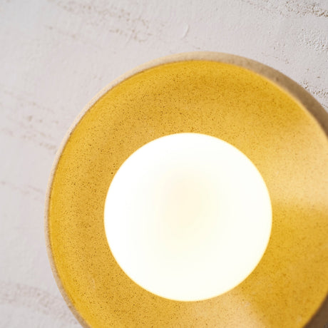 The bowl lit warm, its speckled glaze glowing gold around the globe