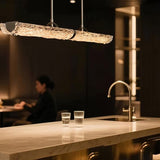 The glass branch lit above a kitchen island beside the tap