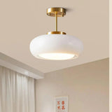 The white glass dome lit on a brass stem beside a pale curtain