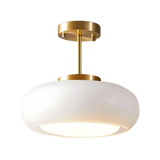 The white glass dome on its brass stem shown against a pale background