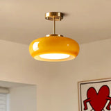 Close view of the yellow glass dome held on its brass stem under a white ceiling