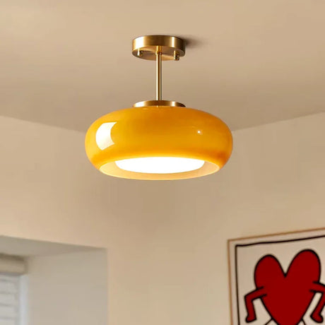 Close view of the yellow glass dome held on its brass stem under a white ceiling