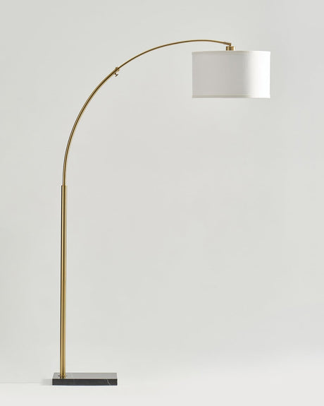 Brass arc floor lamp with a white drum shade on a dark rectangular base