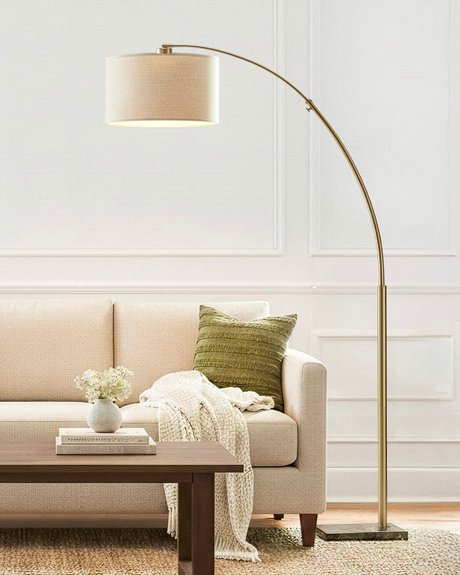 Brass arc lamp reaching over a cream sofa and a low wood coffee table