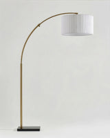 The same brass arc carrying a white pleated drum shade instead of plain linen