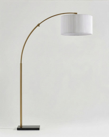 The same brass arc carrying a white pleated drum shade instead of plain linen
