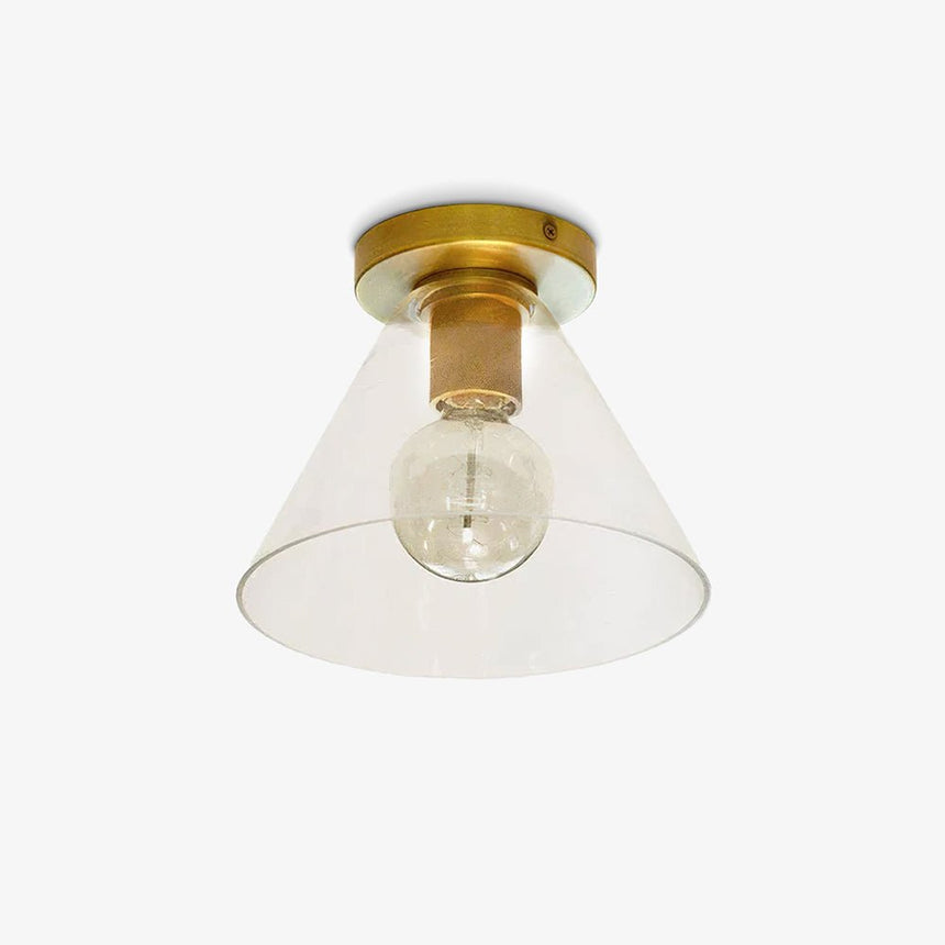 Brass flush mount ceiling light with a clear glass cone shade and an exposed bulb