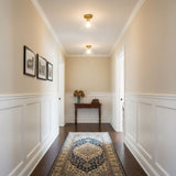 Brass ceiling light in a hallway with framed prints and a console table
