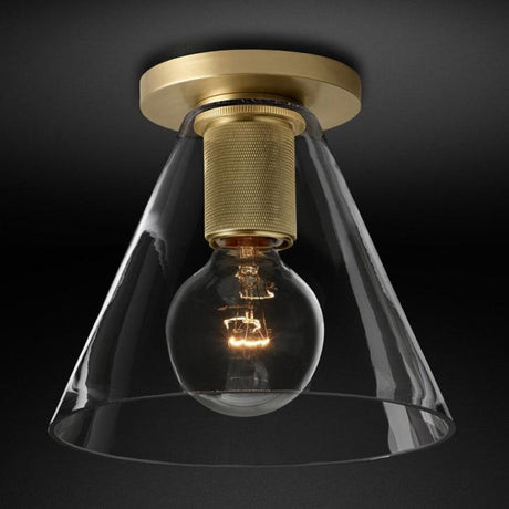 Brass ceiling light with a clear cone shade seen against a dark backdrop