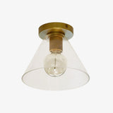 Brass ceiling light with a clear cone shade on a pale backdrop