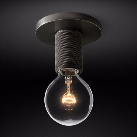 Black ceiling light with an exposed filament bulb against a dark backdrop