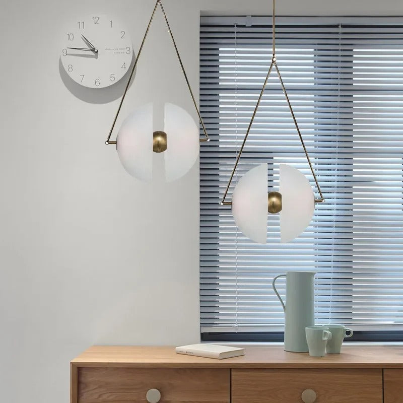 Two brass framed glass discs lit above a wooden sideboard with a mug
