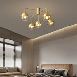 Five globe brass ceiling light above a bed with a leather headboard