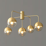 Five globe brass ceiling light with the globes unlit on a gray backdrop