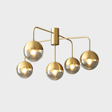 Five globe brass ceiling light seen straight on against a pale backdrop