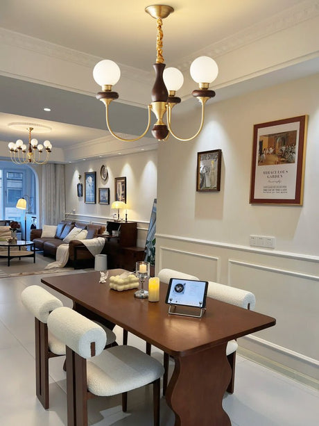 The globes lit above a dark dining table with a laptop and chairs