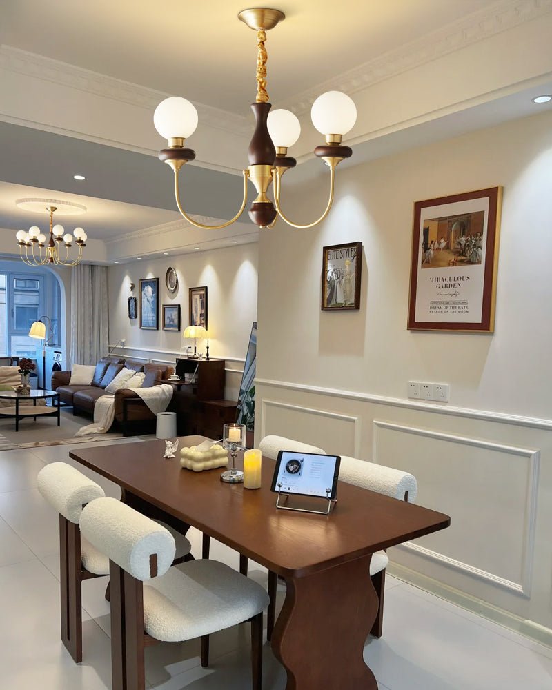 Chandelier lit above a long dining table with pale upholstered chairs