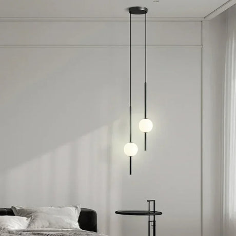 Two globes at staggered heights in a bedroom beside a low side table