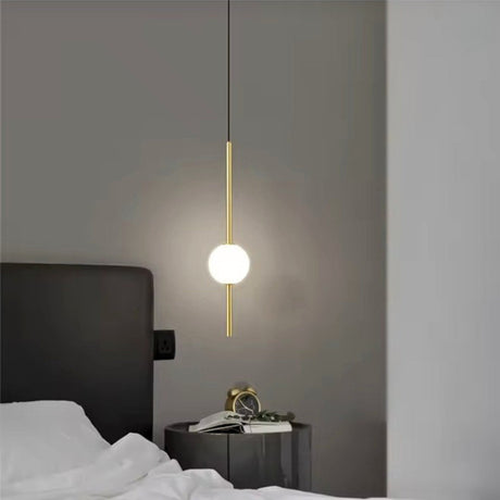A globe on a brass rod hung beside a bed with a dark headboard