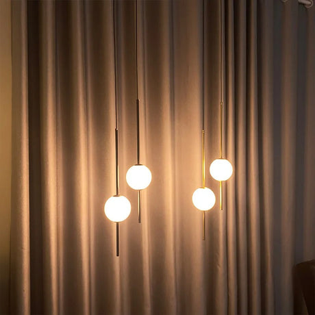 Three globes lit in a row against a long curtain in a dim room