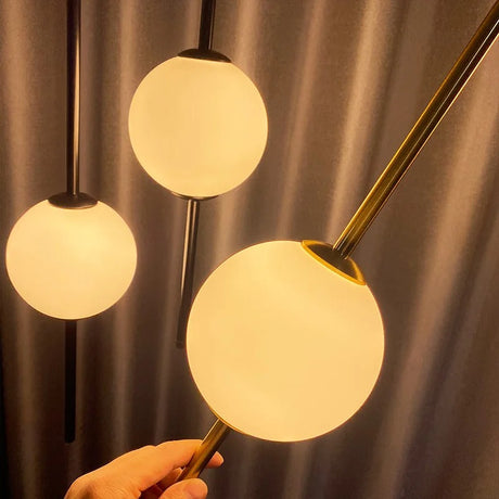 A hand beside two lit globes on brass rods showing how large they are