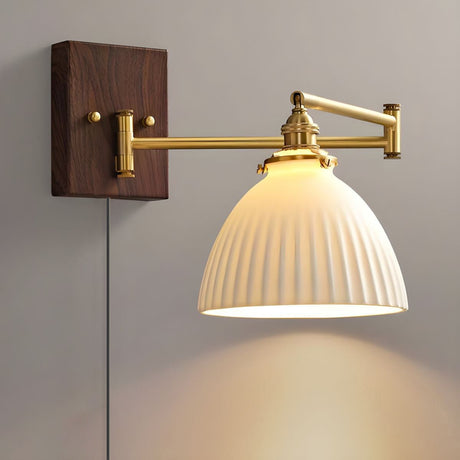 Ceramic dome shade lit from below, brass arm extended from the plate