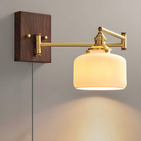 Small ceramic shade lit on a brass arm with the cord running to the floor