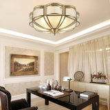 Brass and milk glass ceiling light above a living room with framed art
