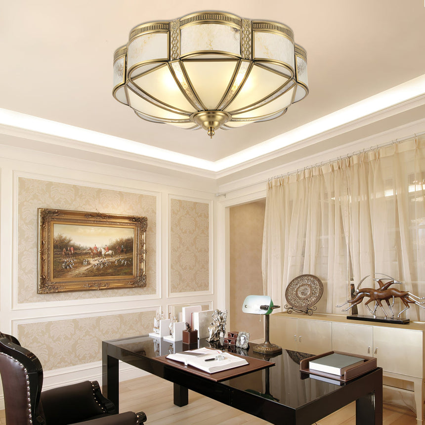 Brass and milk glass ceiling light above a living room with framed art