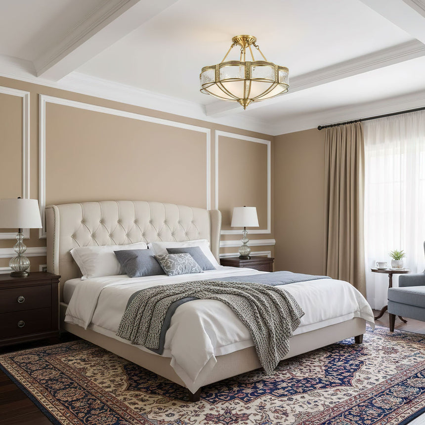 Brass and milk glass ceiling light above a bed with a tufted headboard