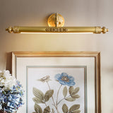Brass bar lit over a gilt framed floral print beside blue hydrangeas in a vase