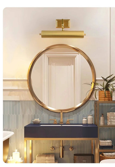 Brass tube above a mirror on a blue vanity cabinet with candles beside it