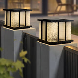 Two lit cubes on fence posts above a slatted boundary at nightfall