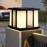 The cube lit on a masonry pillar above a dark fence panel at night