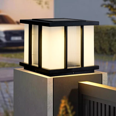 The cube lit on a masonry pillar above a dark fence panel at night