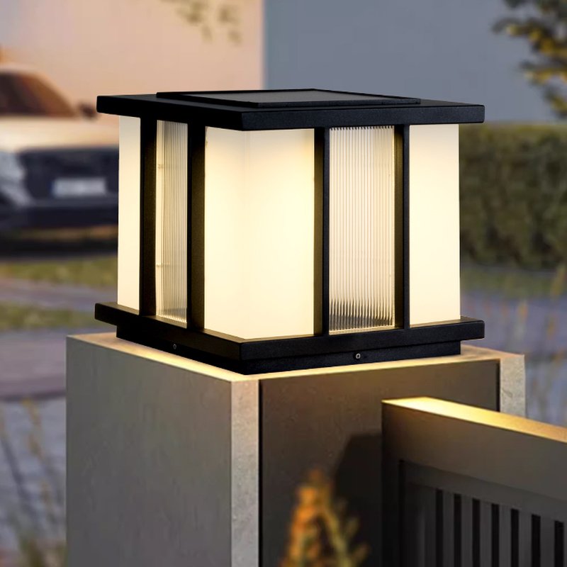 The cube lit on a masonry pillar above a dark fence panel at night