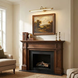 Brass bar lit above a landscape painting over a dark wood fireplace mantel