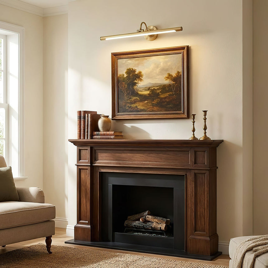 Brass bar lit above a landscape painting over a dark wood fireplace mantel