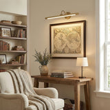 Brass bar lit above a framed map over a console table beside an armchair
