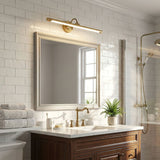 Brass bar lit above a framed mirror on subway tile over a wood vanity unit