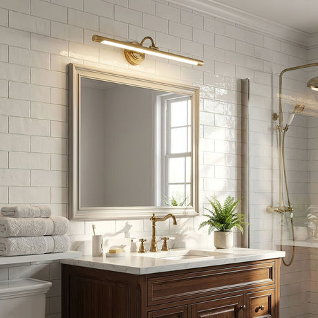 Brass bar lit above a framed mirror on subway tile over a wood vanity unit